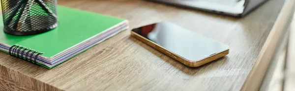 stock image object photo of mobile phone on table next to laptop and pens in stand on notebook, education