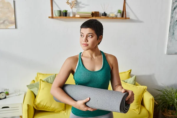 stock image attractive sporty woman with short hair with fitness mat in her living room, fitness and sport