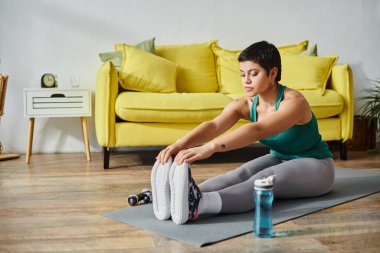 Genç ve güzel bir kadın kaslarını evde aktif olarak geriyor, spor ve spor yapıyor.