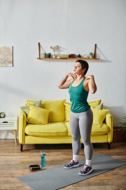 Spor kıyafetleri içinde kısa saçlı, omuzları omuzlarında aktif egzersiz yapan çekici bir kadın.