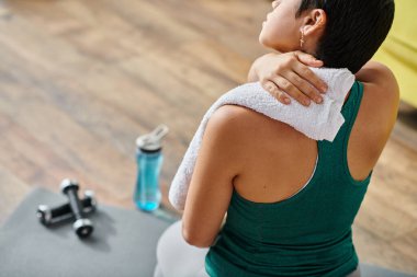 Spor kıyafetli kısa saçlı genç bir kadının egzersiz ve spor sonrası havlu kullanması.