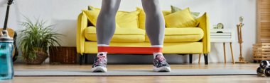 Genç bir kadının spor giyim tarzında direnç bandı, spor ve spor yaparken çekilmiş görüntüsü.