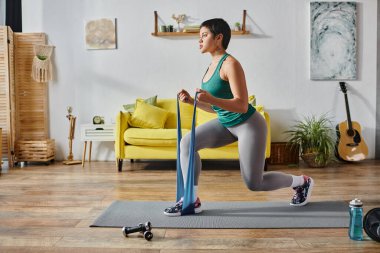 good looking sporty woman with short hair doing lunges using resistance band, fitness and sport clipart