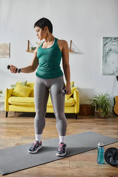 stock image vertical shot of good looking young woman in sportswear working out with dumbbells, fitness