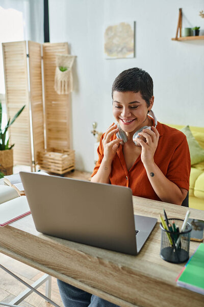 vertical shot of cheerful student in front of laptop attending online classes, education at home