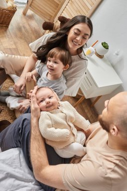 Rahat ev kıyafetleri içinde mutlu bir ailenin yatak odasında birlikte vakit geçirmesi, modern ebeveynlik.