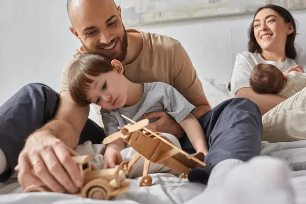 stock image joyful father playing with toys with his little son while his wife looking at them holding baby boy