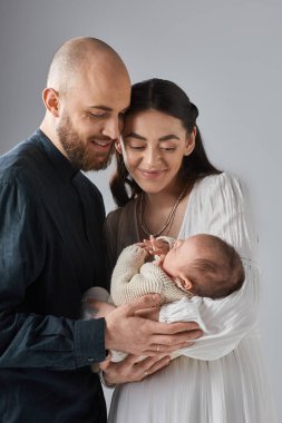 vertical shot of loving young parents holding their newborn baby boy and smiling happily, family clipart