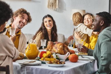 Mutlu çok kültürlü aile ve arkadaşlar Şükran Günü 'nde birlikte tatil yemeği yiyorlar.