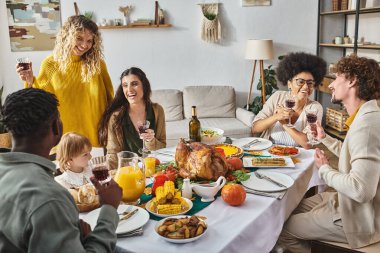 Çok ırklı arkadaşlar ve aile Şükran Günü 'nü yeni yürümeye başlayan küçük kızımızla kutluyorlar.