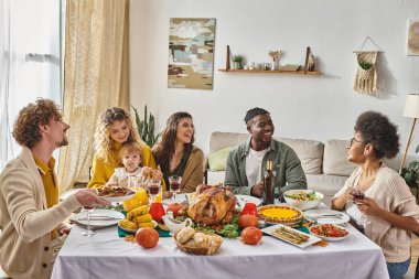 Çok ırklı mutlu arkadaşlar ve aile Şükran Günü yemeği sırasında birlikte vakit geçirirler, hindi