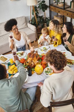 Mutlu çok ırklı arkadaşlar ve aileler Şükran Günü 'nü kutlarken bayram yemeği yiyorlar.
