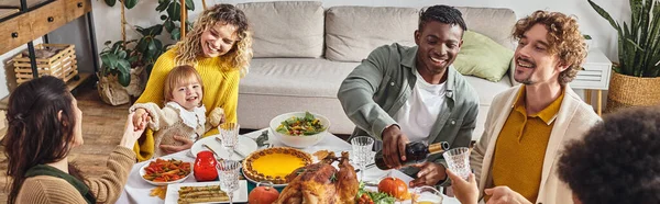 stock image banner, african american man pouring wine into glass of relative, multiethnic friends and family