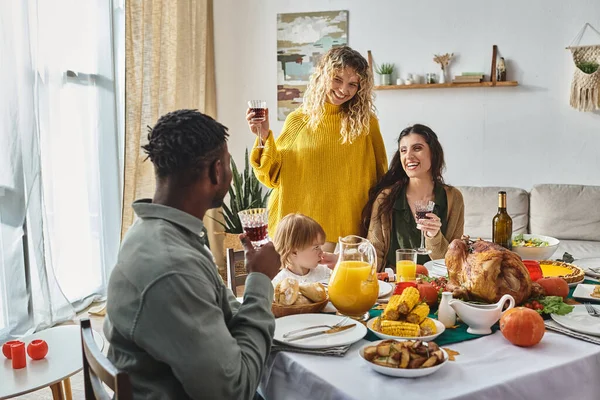 joyful lgbt family celebrating Thanksgiving with toddler baby girl and african american man