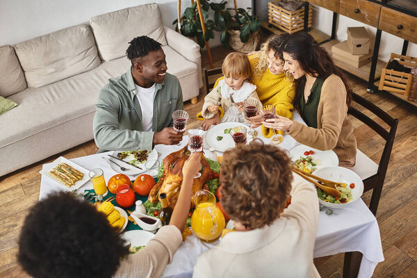 Thanksgiving tradition, smiling multiethnic friends and family cheering glasses of wine, top view