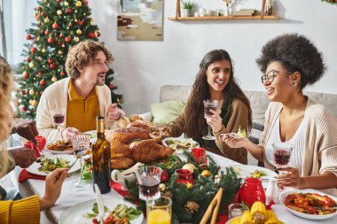 Neşeli çok ırklı aile üyeleri şenlik masasında oturuyor ve neşeli bir şekilde Noel 'i konuşuyorlar.