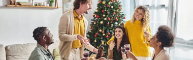 Mutlu çoklu etnik aile şenlik masasında oturmuş şarapla ve etkin bir şekilde konuşarak, Noel, bayrak