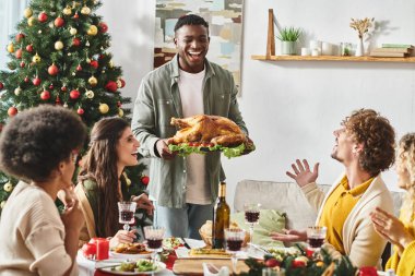Neşeli Afro-Amerikan ailesi elinde hindi ve Noel tabağıyla çevrili.