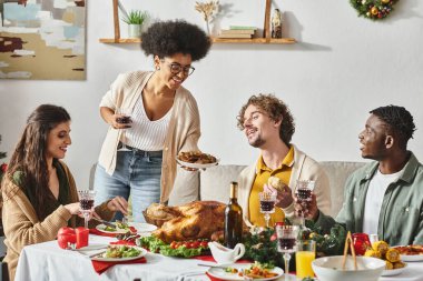 Neşeli çok ırklı akrabalar Noel 'de şarap ve hindiyle ziyafetin tadını çıkarıyorlar.