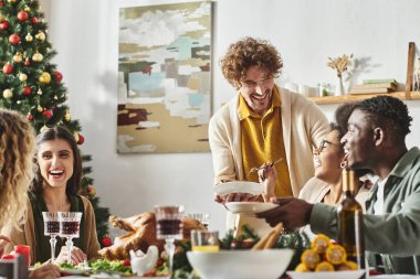 Büyük, neşeli, çok kültürlü bir aile Noel masasında oturmuş gülüyor ve bayram şöleninin tadını çıkarıyor.