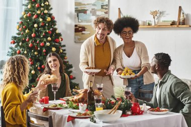 Gündelik giysiler içinde genç, çok kültürlü bir aile Noel 'i birlikte kutluyor ve harika vakit geçiriyorlar.