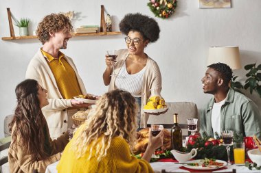 Mutlu aile üyeleri bayram masasında oturup gülümsüyor ve birbirleriyle konuşuyorlar, Noel.