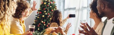 Büyük, çok kültürlü bir aile el sallıyor ve Noel 'de, pankartta selfie çekiyor.