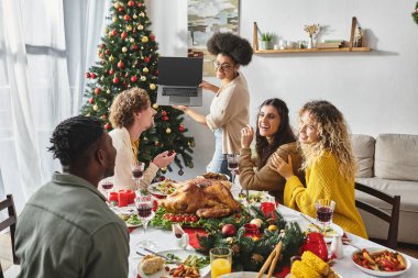 Çok ırklı aile aktif olarak konuşuyor ve Noel 'de dizüstü bilgisayara gülümsüyor.