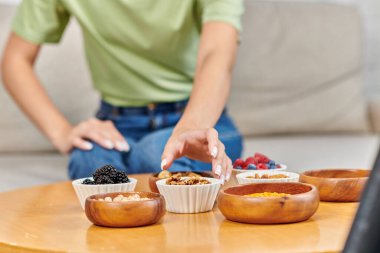 Taze böğürtlen ve baklagillerin yanında ceviz yiyen bulanık bir kadın. Vejetaryenlik.