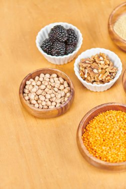 blackberries near walnuts and lentils with chickpeas in bowls on table, plant-based diets, top view clipart