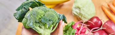 Taze meyve ve sebzelerin üzerinde brokoli olan vejetaryen kadın manzarası, yatay afiş