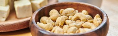 Kestane fıstıklı ahşap kaseye yakın doğranmış tofu peyniri, bitkisel yemek konsepti, afiş.