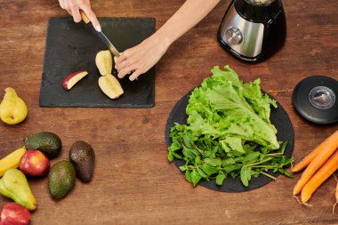 Elektrikli blender yanında elma kesen bir kadın ve naneli marul, bitki temelli diyet