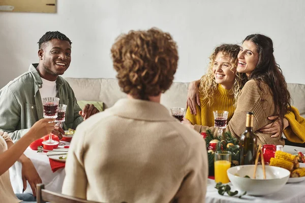 cheerful family members having good time at festive feast hugging and drinking wine, Christmas