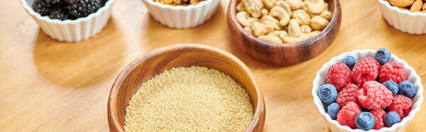 couscous near fresh berries and nuts in wooden bowls, wholesome vegetarian food concept, banner