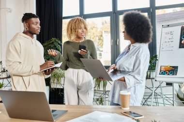 İyi görünümlü günlük giysiler içinde arkadaşlardan oluşan bir ekip projeleri ve iş konseptleri hakkında canlı konuşuyorlar.