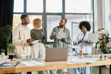 Gündelik kıyafetlerle neşeli bir arkadaş takımı ellerinde defterler, ortak çalışma konsepti olan projeleri tartışıyorlar.