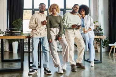 four good looking friends holding cups of coffee and looking confidently at camera, working process clipart