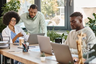 Üç iyi görünümlü arkadaş projelerinde birlikte çalışıyorlar laptoplara bakıyorlar, birlikte çalışıyorlar.