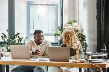 Neşeli genç arkadaşlar projelerinde birlikte çalışıyorlar ve birbirlerine gülümsüyorlar, iş konsepti.