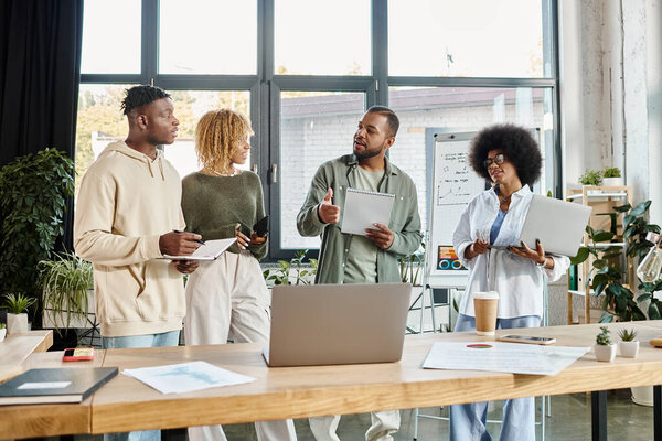 радостная команда друзей в повседневной одежде обсуждают проект с ноутбуками, коворкинг концепция