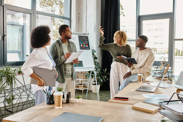 team of jolly friends discussing cheerfully and gesturing while working on project, business