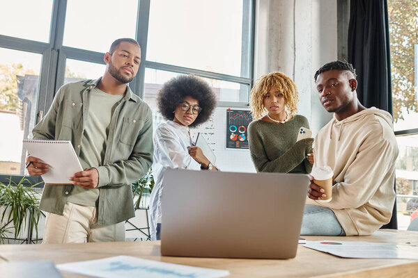 Концентрированные молодые друзья, серьезно глядя на ноутбук во время работы над проектом, бизнес-концепции