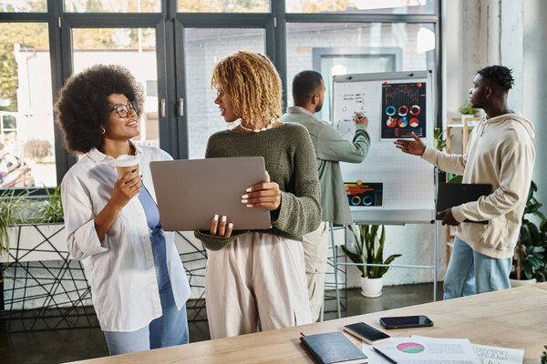 women smiling at each other while working with their male friends on backdrop, business concept