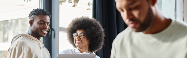 vertical shot of focused man with his friends working cheerfully on backdrop, coworking, banner
