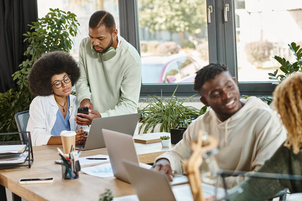 cheerful team of friends in casual wear smiling and discussing their project, working process