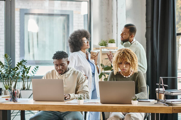 good looking man and woman working with their colleagues discussing project on backdrop, coworking