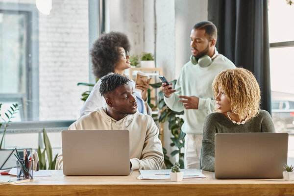 четыре африканских американских друга в повседневной одежде обсуждают свой проект активно, рабочий процесс