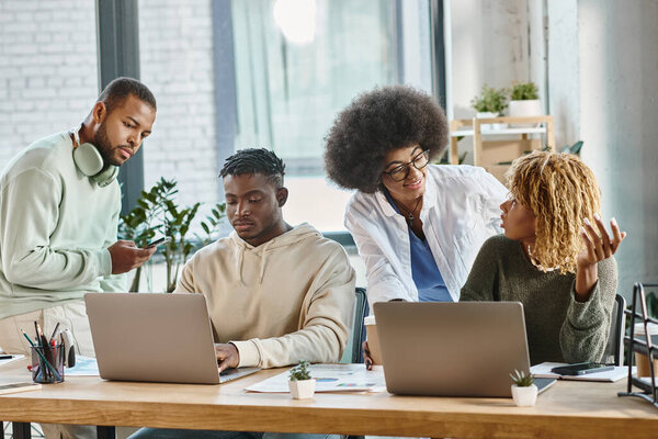 two women smiling at each other while their male friends looking ta laptop, business concept