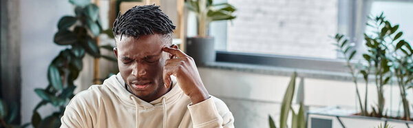 концентрированный и озадаченный африканский американец с рукой рядом с храмом, рабочий процесс, баннер